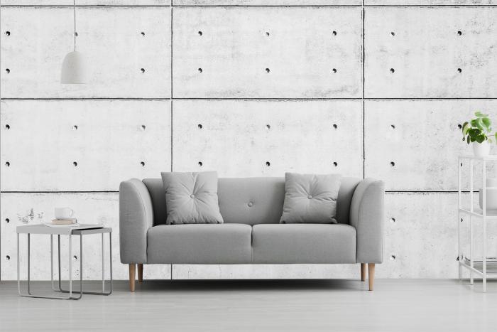 Vlies-Fototapete hellgraue Betonwand aus Plattenelementen mit Löchern in einem Wohnzimmer