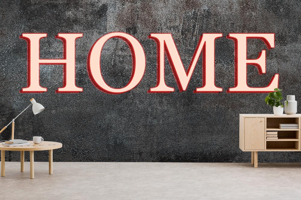 Vlies-Fototapete „Home“ als Schriftzug auf einer dunklen Betonwand in einem Wohnzimmer